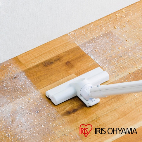白色輕量吸塵器吸頭正在清潔木質地板上的灰塵與碎屑，地板呈現自然木紋。