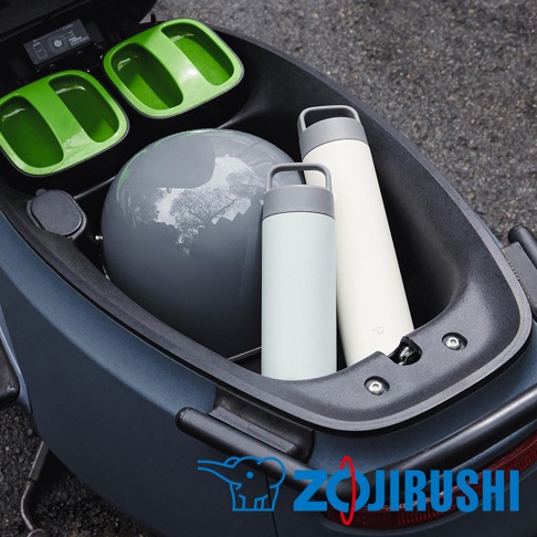 0.6L不鏽鋼真空吊環保溫保冷杯，一淺藍色、一象牙白色，杯蓋皆為灰色，置於摩托車置物箱內，旁有一灰色安全帽及兩個綠色收納盒。