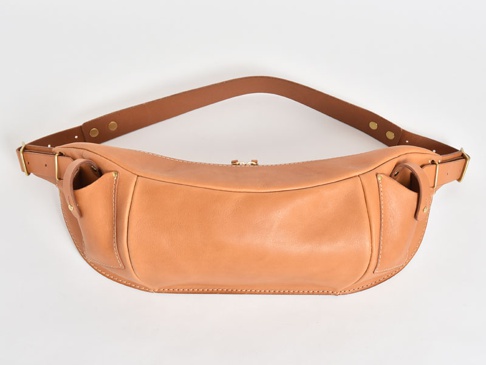 淺棕色皮革製作的彎月形斜背包，配有可調節的皮革肩帶和金屬扣環。包身兩側有外插袋，頂部有拉鍊開合。
