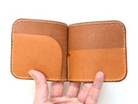 職人手作皮革短夾，淺棕色，橫式對折設計，內有兩格卡槽，並以金色夾子固定，皮革質感，手工縫線。