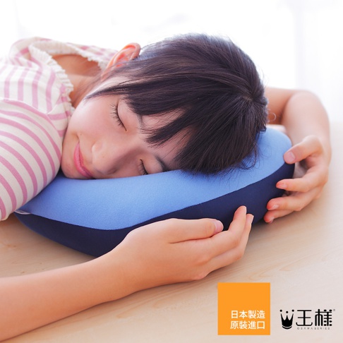 一位年輕女子頭部枕在藍色與深藍色拼接的U型枕上，枕頭表面材質看起來柔軟。