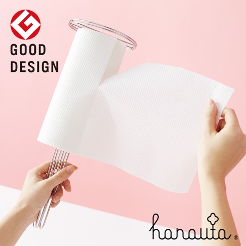 不鏽鋼立式紙巾架，簡約的銀色金屬支架，穩固支撐著一捲白色紙巾，左手持架，右手拉取紙巾。