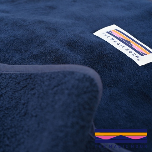 深藍色毛絨睡袋毯，帶有標誌性彩色幾何圖案織標。