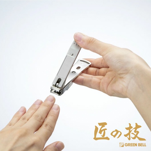 一隻手拿著鍛造不鏽鋼寬刃集屑指甲剪，剪刀的刀刃對準另一隻手的指甲。指甲剪為銀色金屬材質，設計簡潔，帶有集屑功能。