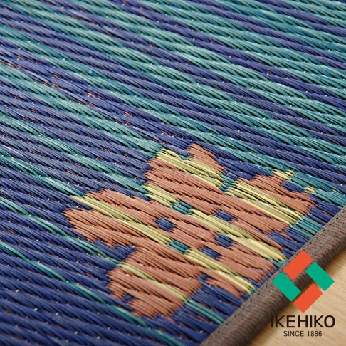 藺草編織的瑜珈墊，以藍色、綠色、橘色和黃色線條交織出富士山圖案，邊緣有灰色包邊。