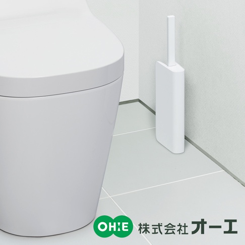 白色超薄浴廁清潔刷，刷柄直立收納於簡潔的白色方形筆筒式刷座內，放置於白色磁磚牆角與地面旁，一旁為部分白色的馬桶。