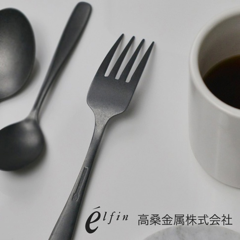 日製熔岩黑石餐叉，呈現深邃的黑色調，材質似金屬，表面帶有細緻的紋理。餐叉共有四個叉齒，造型簡約，散發出沉穩的質感。