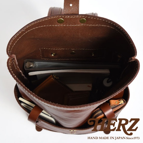 職人手作皮革雙口袋折蓋後背包 R-301，展示內部空間，內有文件夾、筆記本、皮夾和拉鍊零錢包，材質為棕色皮革。