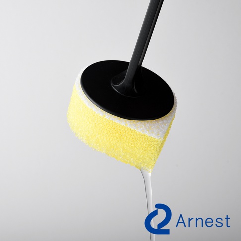 Arnest 的直角鍋專用不沾手防刮清潔海綿，黃色海綿搭配黑色手柄，清潔海綿末端有水滴下。