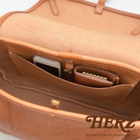 職人手作皮革大容量扣環郵差包，展示包內結構，淺棕色牛革材質，可見手機及零錢包收納夾層，做工精緻。