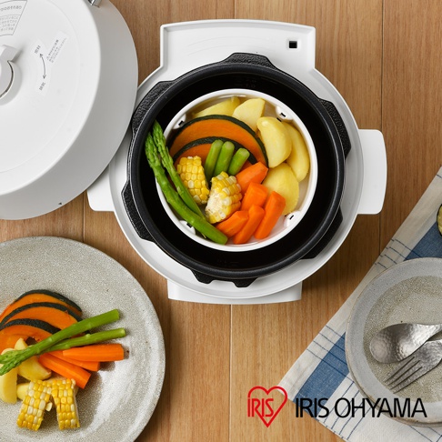 白色電子壓力鍋內盛放著蒸熟的什錦蔬菜，包含南瓜片、玉米段、蘆筍、紅蘿蔔塊和馬鈴薯塊。