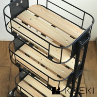 黑色金屬框架的Mash三層置物收納推車，每層皆有淺木色條狀木板，推車底部有滾輪，整體為簡約實用的設計。