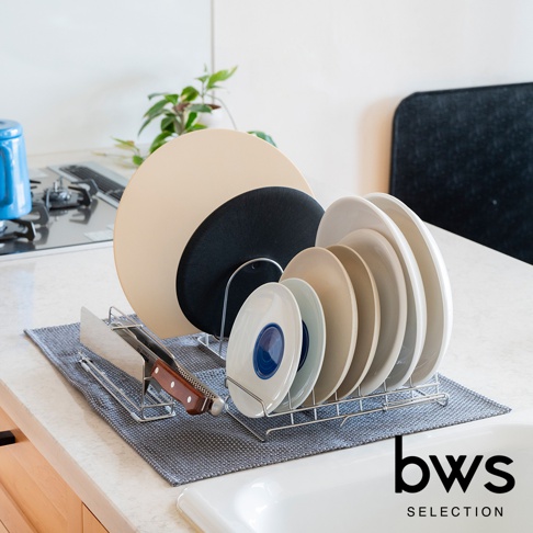 bws SELECTION 不鏽鋼瀝水架上擺放著數個大小不同的盤子，左側有一個木柄的刀具。