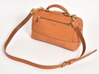 職人手作皮革兩用迷你口金單肩包，採用天然棕色皮革製成，配有金色金屬配件和可拆卸肩帶。包身線條簡潔，縫線清晰，正面有一個拉鍊口袋。