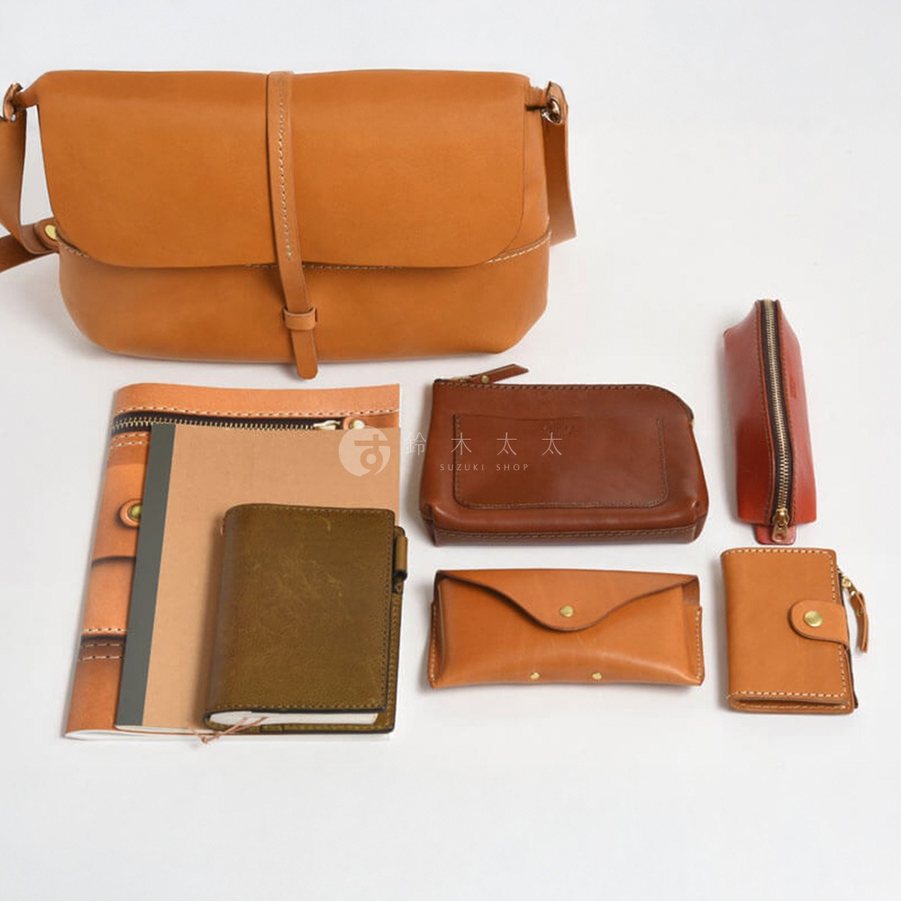 多個棕色皮革製品，包含一個斜背包、一個筆袋、一個夾層包、一個長夾、一個短夾以及兩個筆記本。