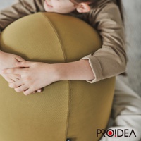 一位女孩的雙手環抱著一個黃綠色的彈力平衡球，球體表面為針織紋理，整體呈現圓潤的造型。