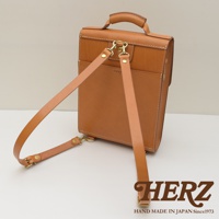 職人手作皮革復古後背包，採用棕色皮革製成，具有可調節的肩帶和金屬扣環，背面有品牌標誌。