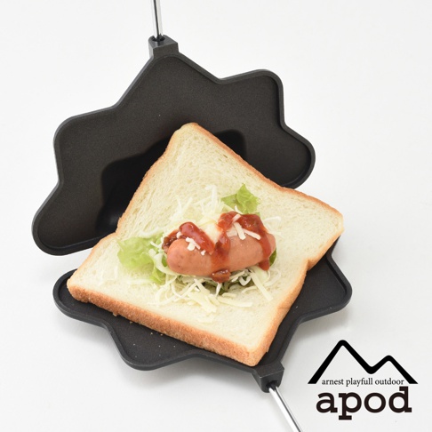 黑色星形熱壓三明治烤夾，夾著一片吐司，內餡為切片香腸、高麗菜絲及起司，並淋上番茄醬。