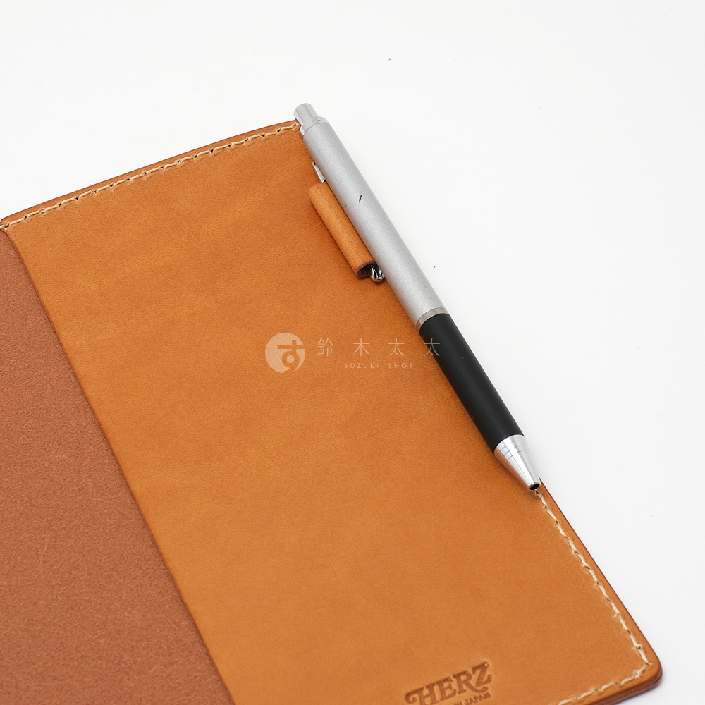 職人手作皮革B6記事本書套，採天然皮革，呈現溫潤的棕色調，搭配銀色金屬筆，整體質感簡約。