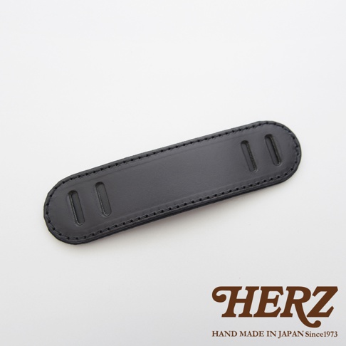 黑色皮革製成的肩墊，表面平滑，有兩條縫線，兩端各有一對長方形的孔洞，設計簡潔，適合搭配各式包款。