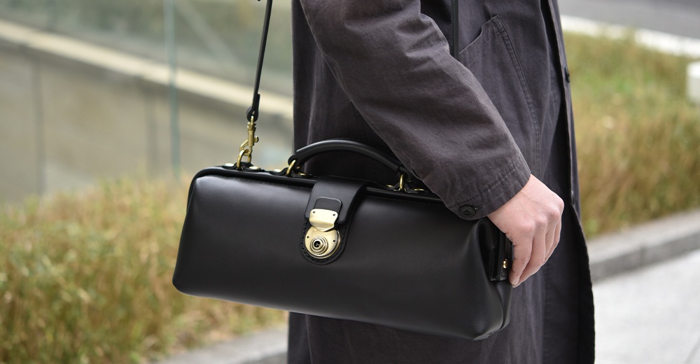 日本HERZ職人手作黑色皮革橫長形單肩包，配有金色旋轉鎖扣和手提握把。