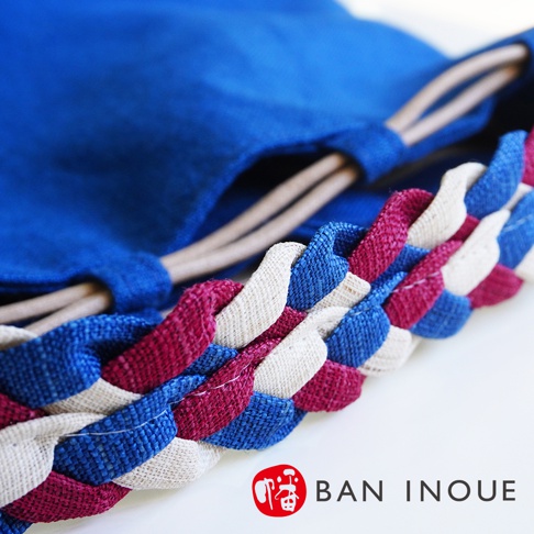 BAN INOUE 品牌標誌旁的編織細節，由藍色、酒紅色和米白色布條交織而成。