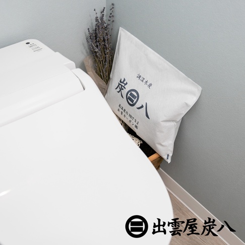 白色方形布袋裝有調濕木炭，袋上印有黑色日文「調濕木炭」及「炭八」。袋旁有乾燥的薰衣草束。