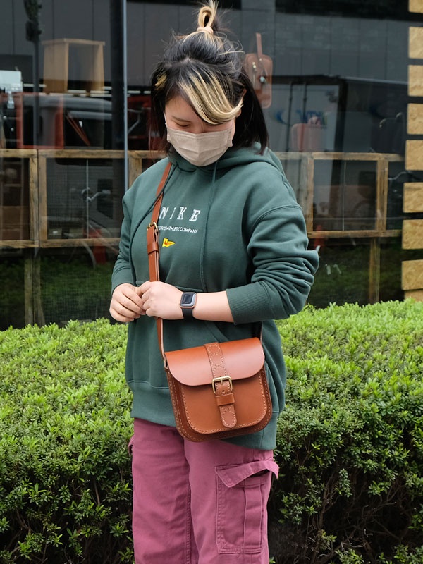 棕色皮革單肩包，方形包身，帶有翻蓋和黃銅色搭扣，肩帶可調節。