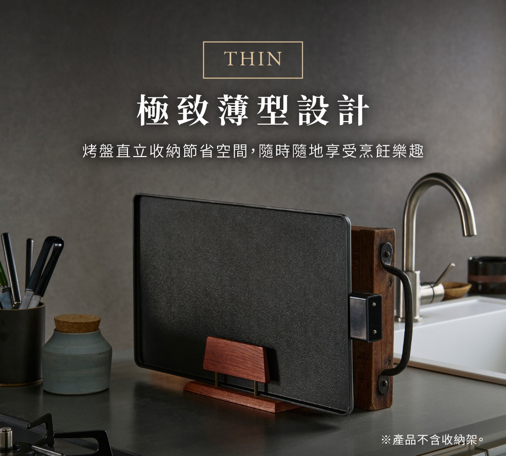 黑色輕薄電烤盤，表面帶紋理，搭配木質支架，側面有金屬提把，置於廚房檯面上，背景為水槽與水龍頭。