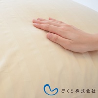 手輕觸淺米色條紋紋理的枕套，布料呈現細緻的織紋。