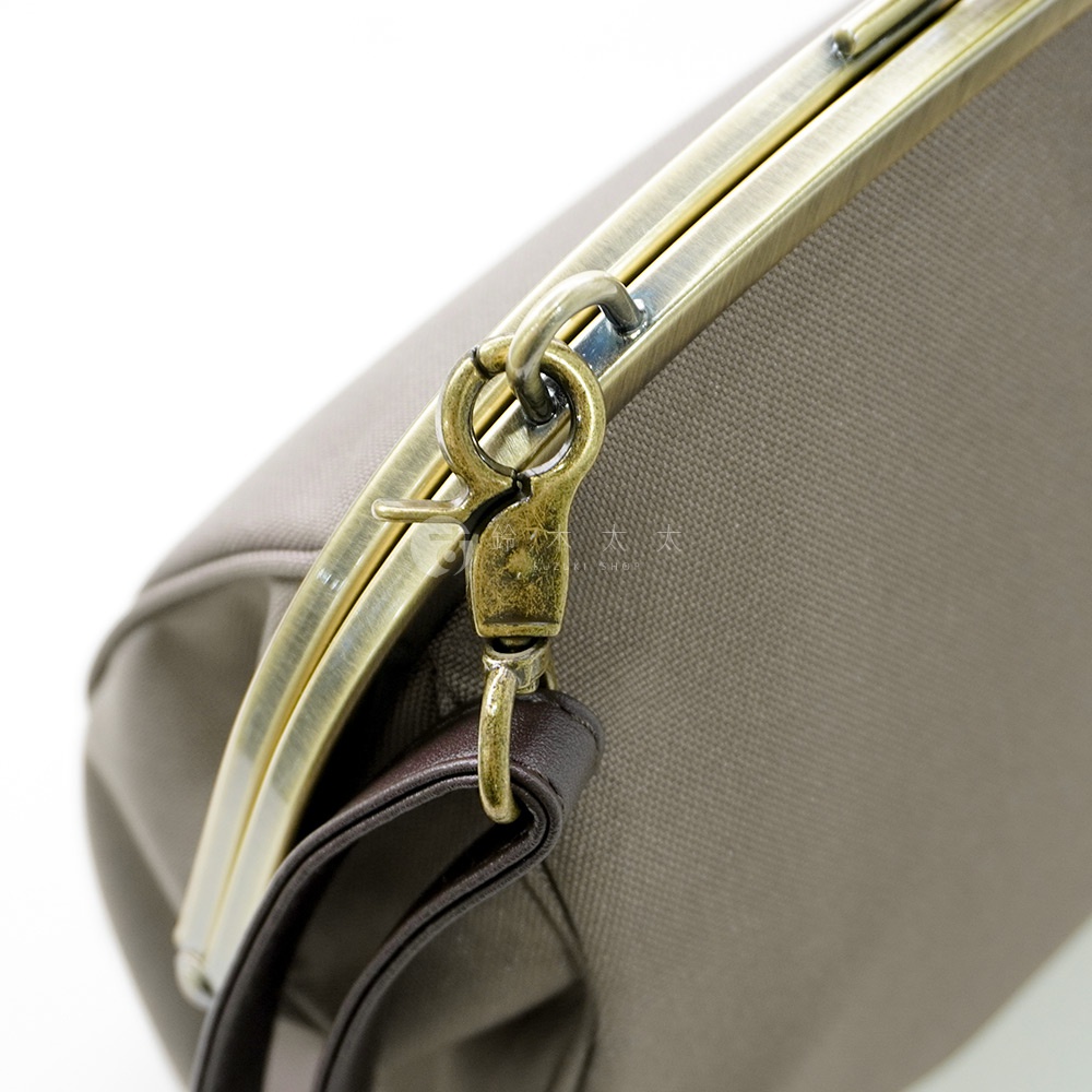 京都職人手作大玉口金斜背包，側面特寫，展示古董金色金屬扣和棕色皮革帶。