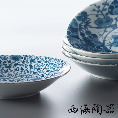 白色陶瓷淺盤，內側繪有藍色纏枝花卉與蓮花圖案。盤緣有細微的藍色線條裝飾，堆疊的盤子展示了不同的藍色植物和花鳥圖案。