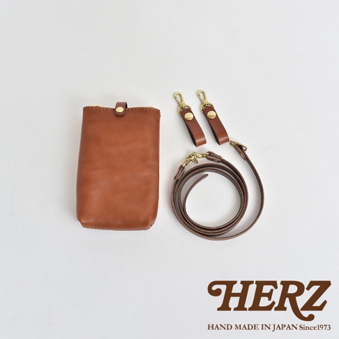 職人手作皮革手機包，顏色為棕褐色，附有兩條皮質背帶和黃銅金屬扣環。