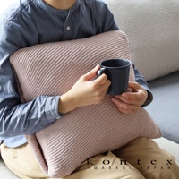 粉色羅紋針織彈性枕套，質地柔軟，觸感舒適。一人抱著枕頭，手持黑色馬克杯，坐在沙發上。