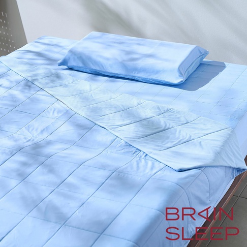 淺藍色極冷涼感被EX，表面有菱格紋填充，搭配同色系枕頭，鋪設在木製床架上，整體呈現簡潔舒適的睡眠氛圍。