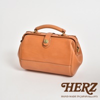 職人手作皮革口金醫生單肩包，以淺棕色皮革製成，配有金色旋轉鎖扣及金屬腳釘，頂部設有皮革提把，整體風格復古。