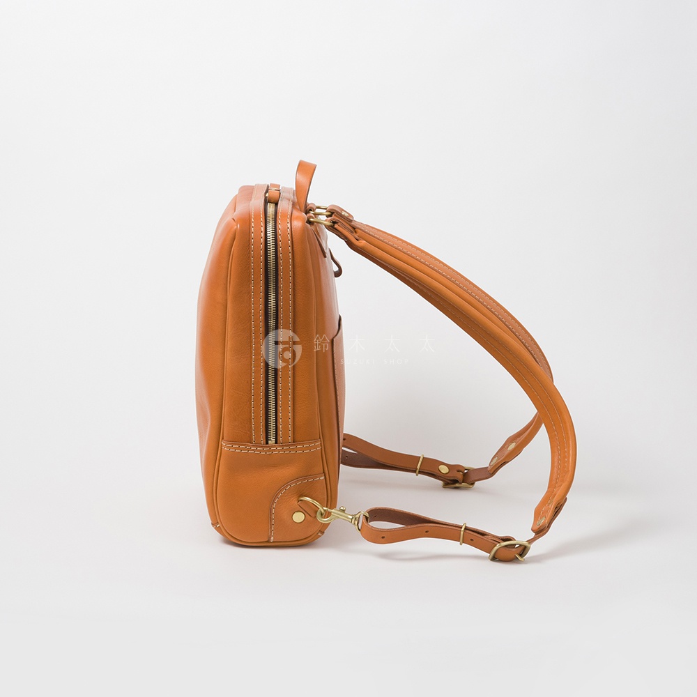 棕色軟皮商務後背包，側面視角，展示拉鍊、皮革材質與金屬扣環。