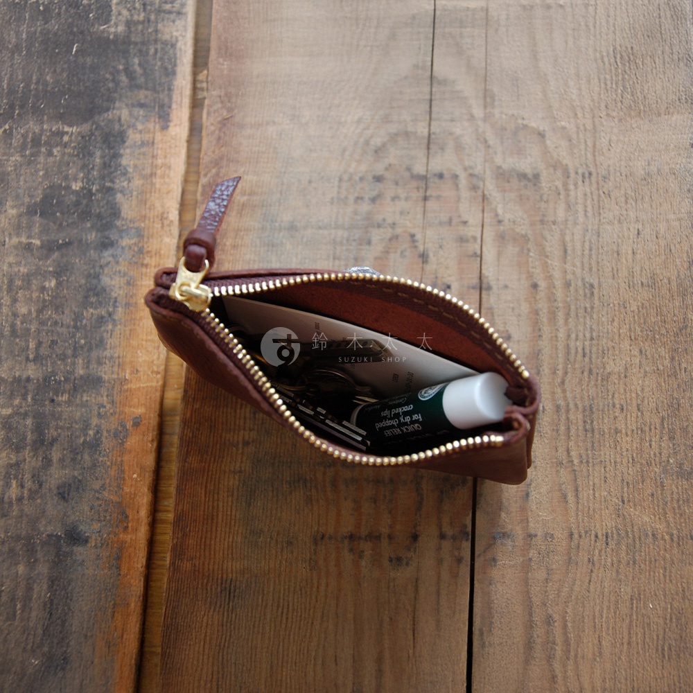 職人手作皮革Organ拉鍊式小物收納袋，深棕色皮革，金色拉鍊，袋內有鑰匙和護唇膏。