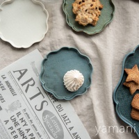 美濃燒花型甜點盤，有白色、綠色和藍色三種顏色。盤子邊緣呈波浪狀，盤面有細密的格紋紋理，材質疑似陶瓷。其中藍色盤子中擺放著白色蛋白霜餅乾，綠色盤子中擺放著巧克力餅乾，右側另有藍色盤子擺放著星形餅乾。