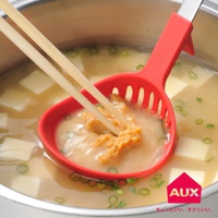 紅色不沾桌多用濾水湯匙，包含湯匙頭的側邊濾孔，用兩根木質筷子夾著味噌，在裝有豆腐和蔥花的湯鍋中操作。