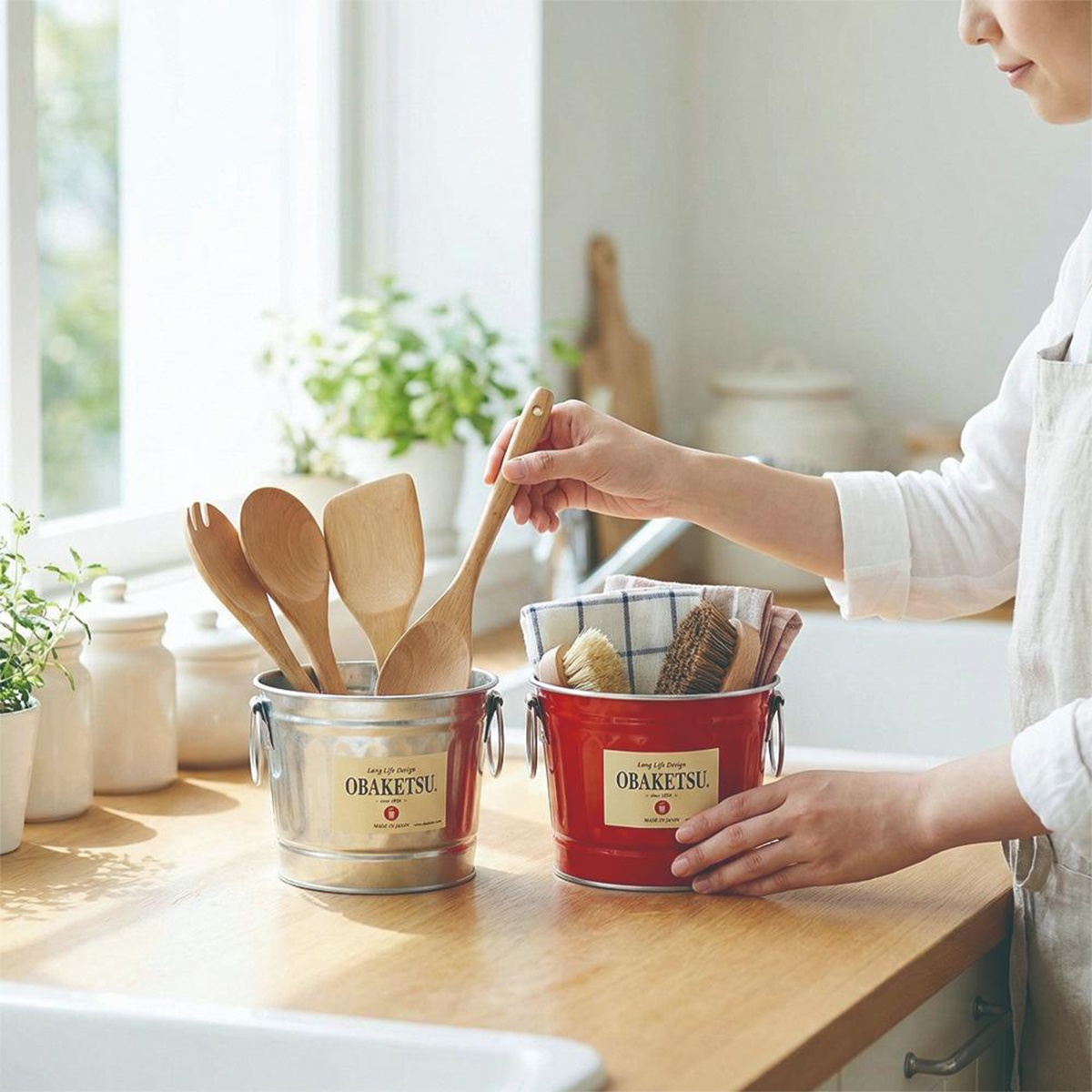 OBAKETSU 手工製多功能迷你桶，銀色桶內盛放木製料理用具，紅色桶內則裝有清潔刷具與方巾