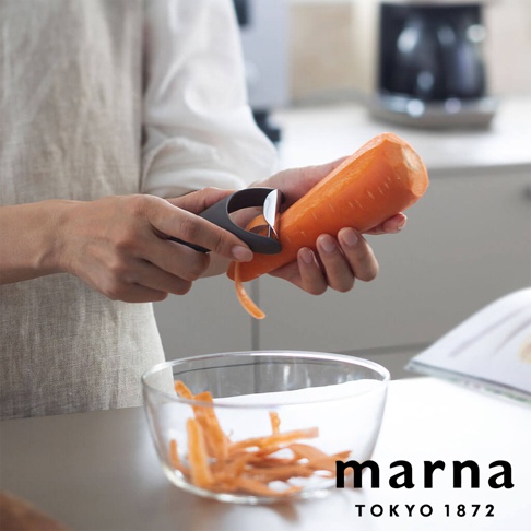 marna 多功能削皮器正在削胡蘿蔔，削下的胡蘿蔔絲落入玻璃碗中