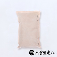 淺褐色布質包裝的寬版調濕木炭，表面有細小的網狀紋路，側邊縫線清晰，印有品牌標誌與文字，整體為長方形的居家收納用品。