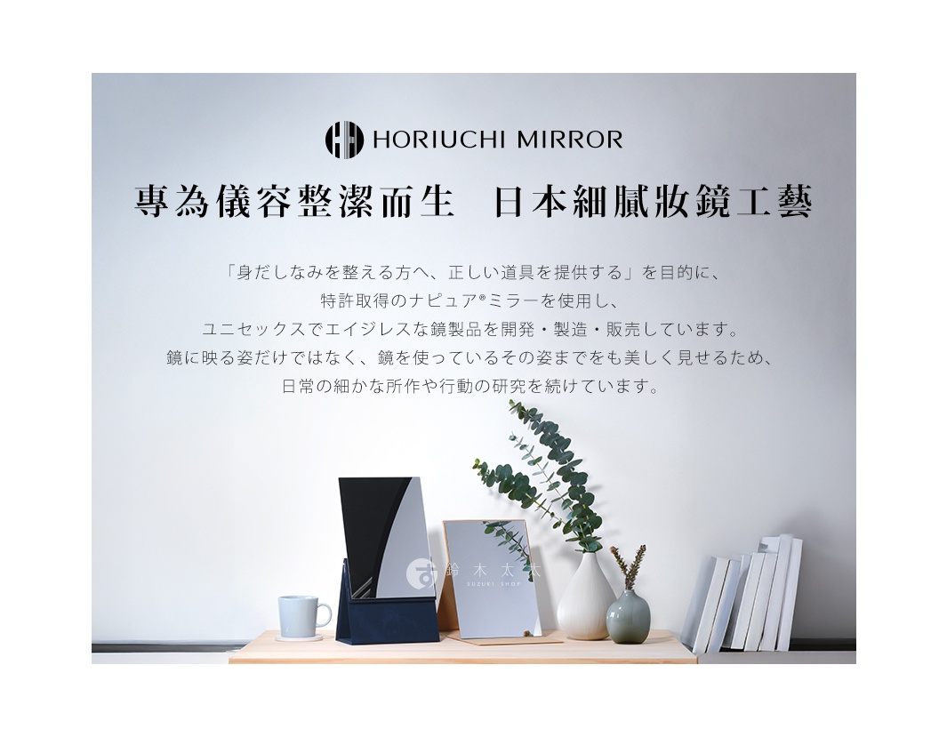 深藍色底座上的銀色鏡面化妝鏡，鏡面上有一個圓形標誌，旁邊有一個淺藍色馬克杯和一本白色書籍。