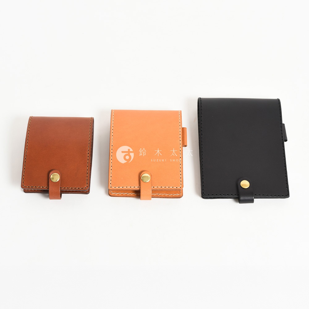 三款職人手作皮革便利貼收納套，分別為深棕色、橘色及黑色，皆採用皮革材質，搭配金色按扣，設計簡約。