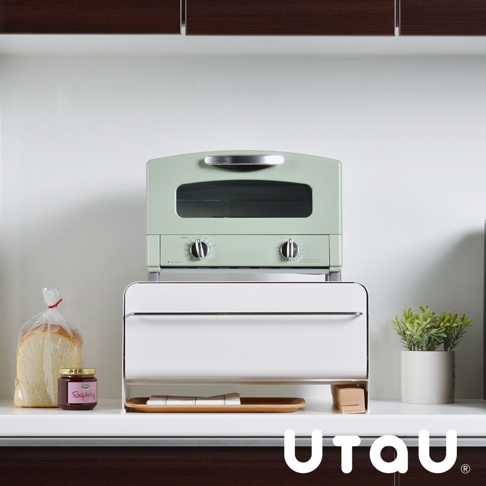 抽屜式收納整理櫃，白色，配有銀色把手，上方堆疊綠色烤箱。櫃子下方放置木質托盤，托盤上有餐巾，旁邊有果醬罐和一袋吐司。