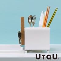 白色方形瀝水架，內含不鏽鋼湯匙、叉子、兩雙筷子（一雙橘色、一雙綠色）及白色盤子，架旁掛著木質砧板。