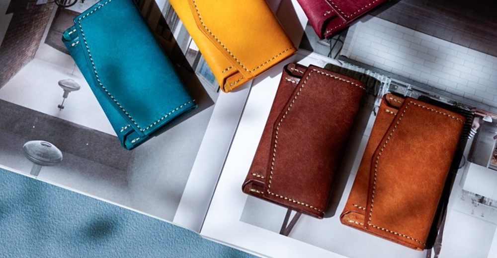 北海道KASANE職人手作義大利Margot皮革迷你雙折短夾，共五種顏色：藍綠、黃色、酒紅色、深棕色與橘棕色，展示於雜誌畫報上。