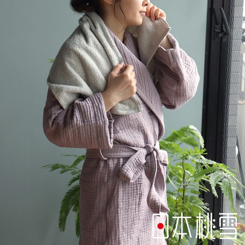 身著淡紫色雙面紗布立體織紋輕質浴袍，腰間繫有同色腰帶，右肩披著一條淺灰色毛巾。