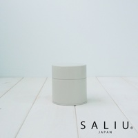 簡約淺灰色的圓柱形錫製茶葉罐，帶有蓋子，罐身有細緻的接縫線，放置於白色木紋桌面上。